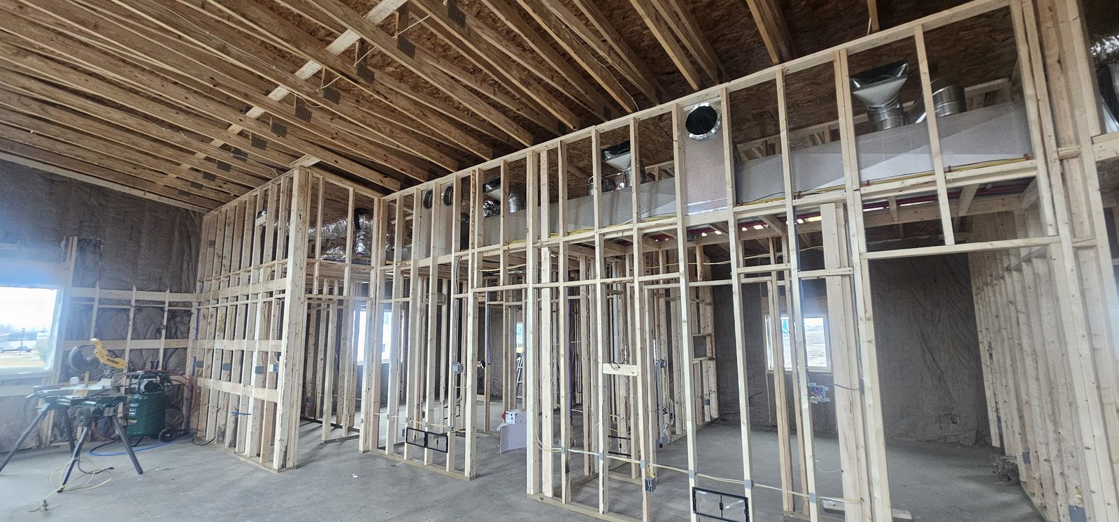 Interior view of a barndominium barndominium during framing, showing the metal underside and truss assembly