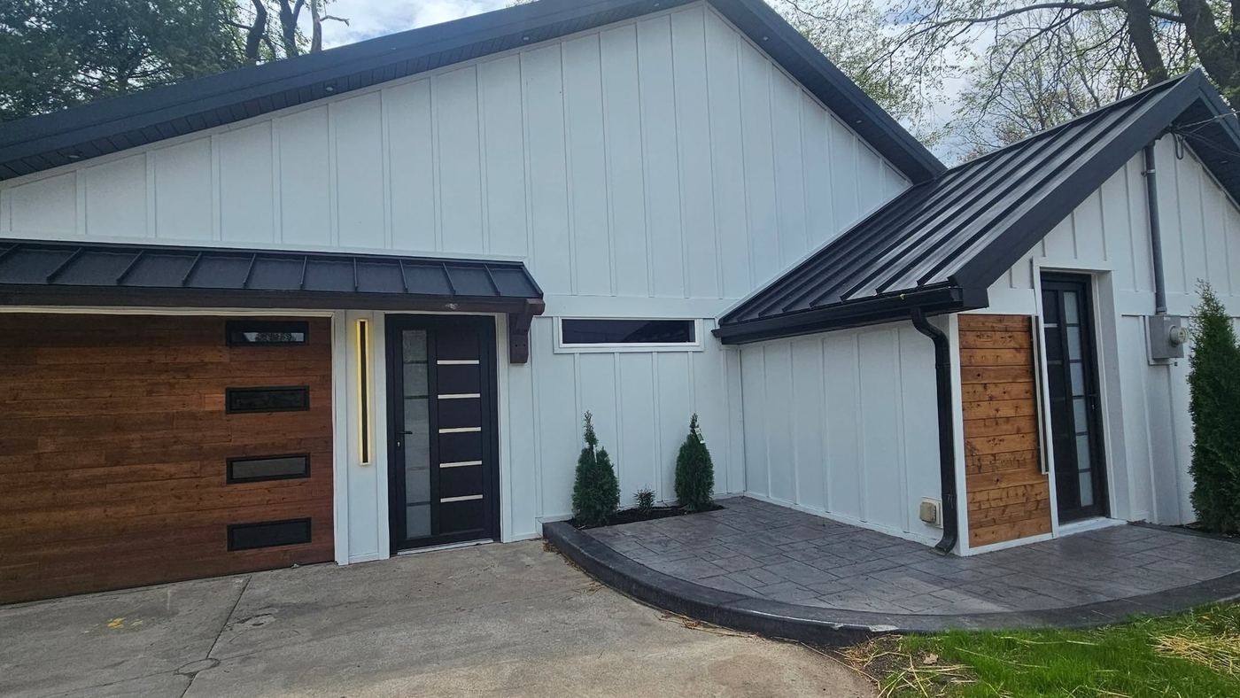 White Battenlok board and batten steel siding on a modern home in Michiana, with black standing seam accents and cedar entry doors
