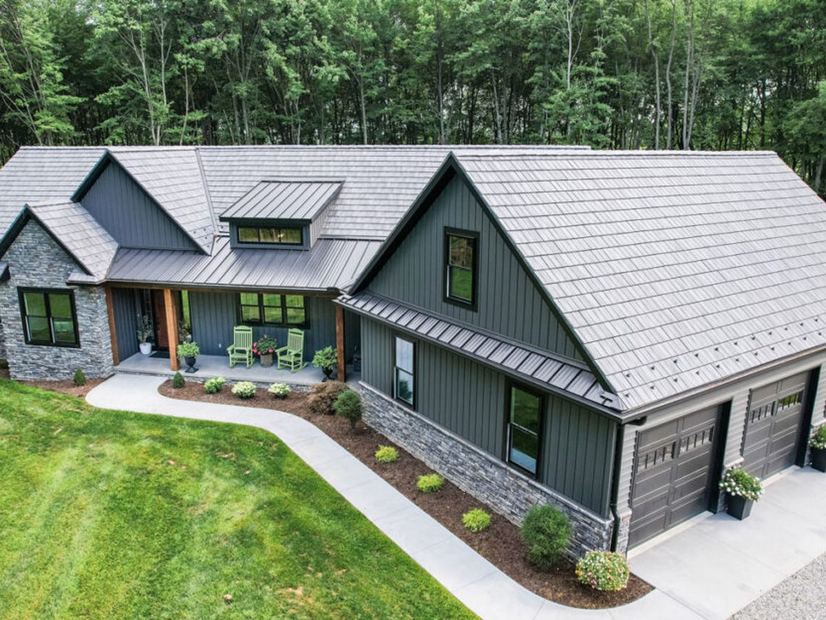 Ranch home with stone and board and batten siding under a gray stamped metal shingle roof